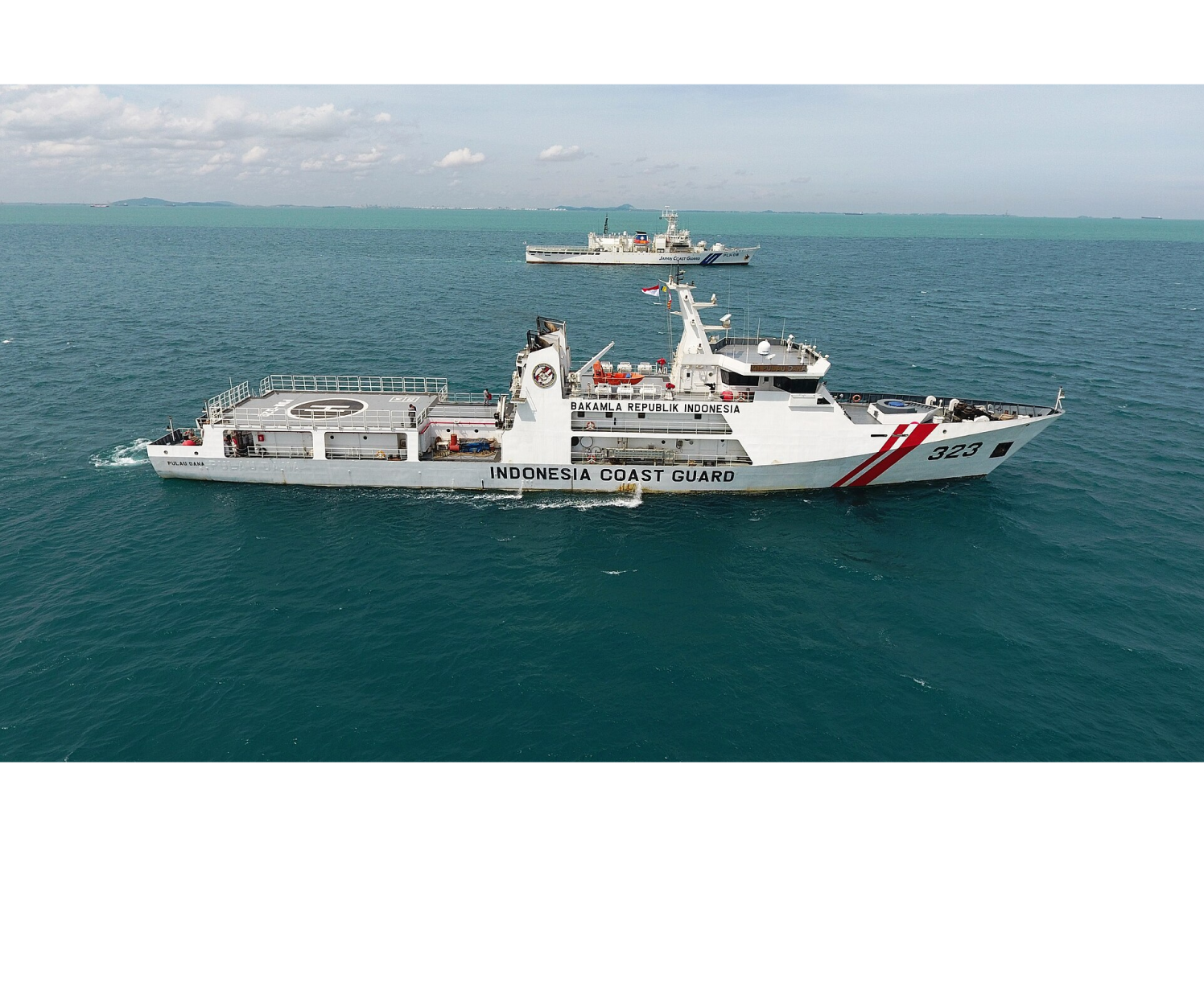 An photograph depicts two coast guard ships sailing on blue waters. One ship is in the foreground and one ship is in the background. The ship in the foreground reads, “INDONESIA COAST GAURD” on the side. It also reads “323” at the front of the ship and has two stripes near the front.

The black text reads, “February 2, 2022

Indonesian and Japanese ships conduct anti-piracy exercises in the Singapore Strait.”