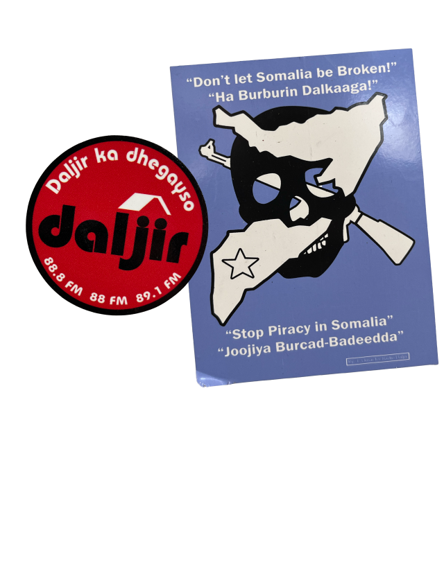 Two stickers are shown in a collage in the right column. One sticker is a rectangle with a light blue background. It has a black skull clip art with a white silhouette of a gun and the boundaries of Somalia crossing through the sockets of the skull. At the top of the sticker in white text in english it reads, “Don’t let Somalia be Broken!” under this text is a translated version in Somali. At the footer of the sticker the white text reads, “Stop Piracy in Somalia” with a translated version beneath it. 

There is a watermark for One Earth Future in the bottom right corner.

The second sticker is a circle. It is red with a black  border. White text in somali borders the top of circle while a logo reading “daljir” in black is in the middle. White text with the radio FM code is on the bottom of the sticker. 

The left column of the graphic explains, “Stickers from 
One Earth Future’s campaign against piracy in Somalia.”